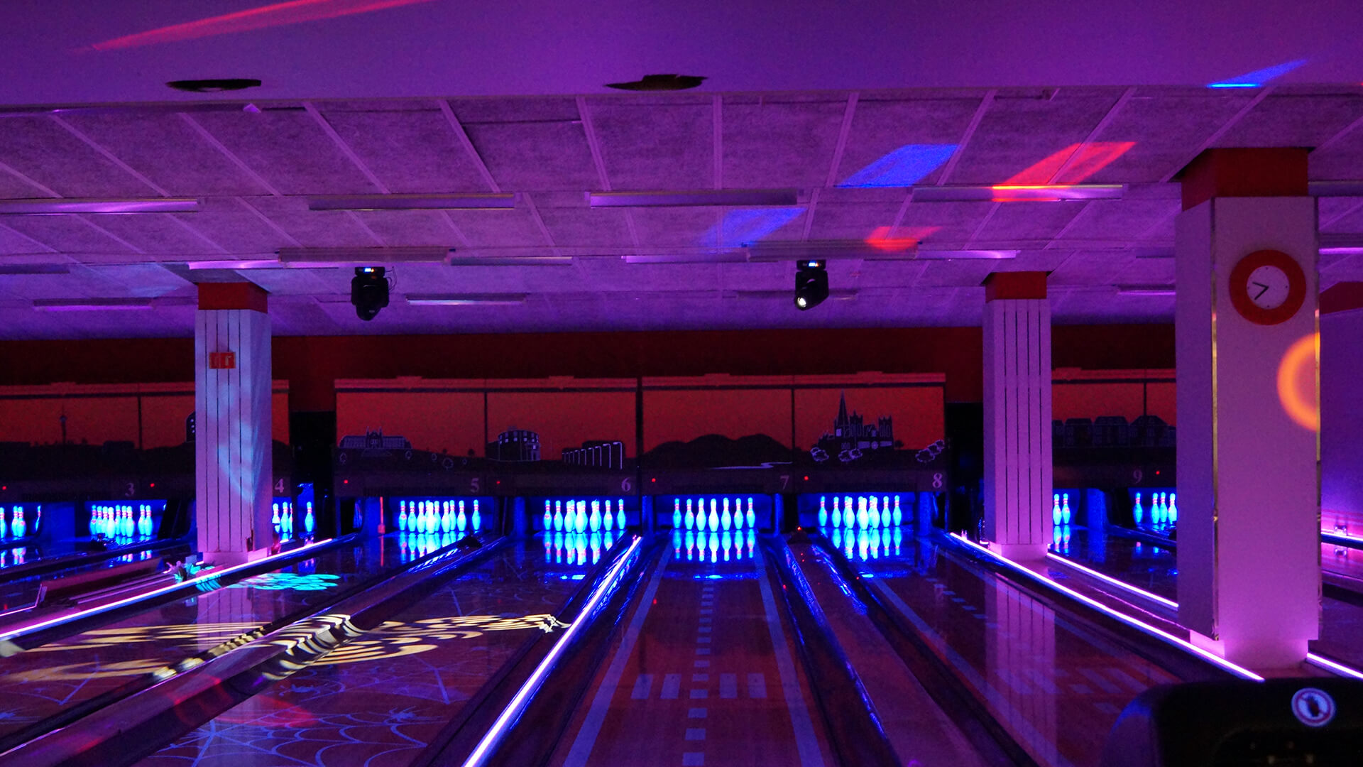 Centrum Bowling — full oversikt over 10-banes hallen i kveldsmodus med blå pinne-belysning og terrakottavegg med Trondheim-silhuett